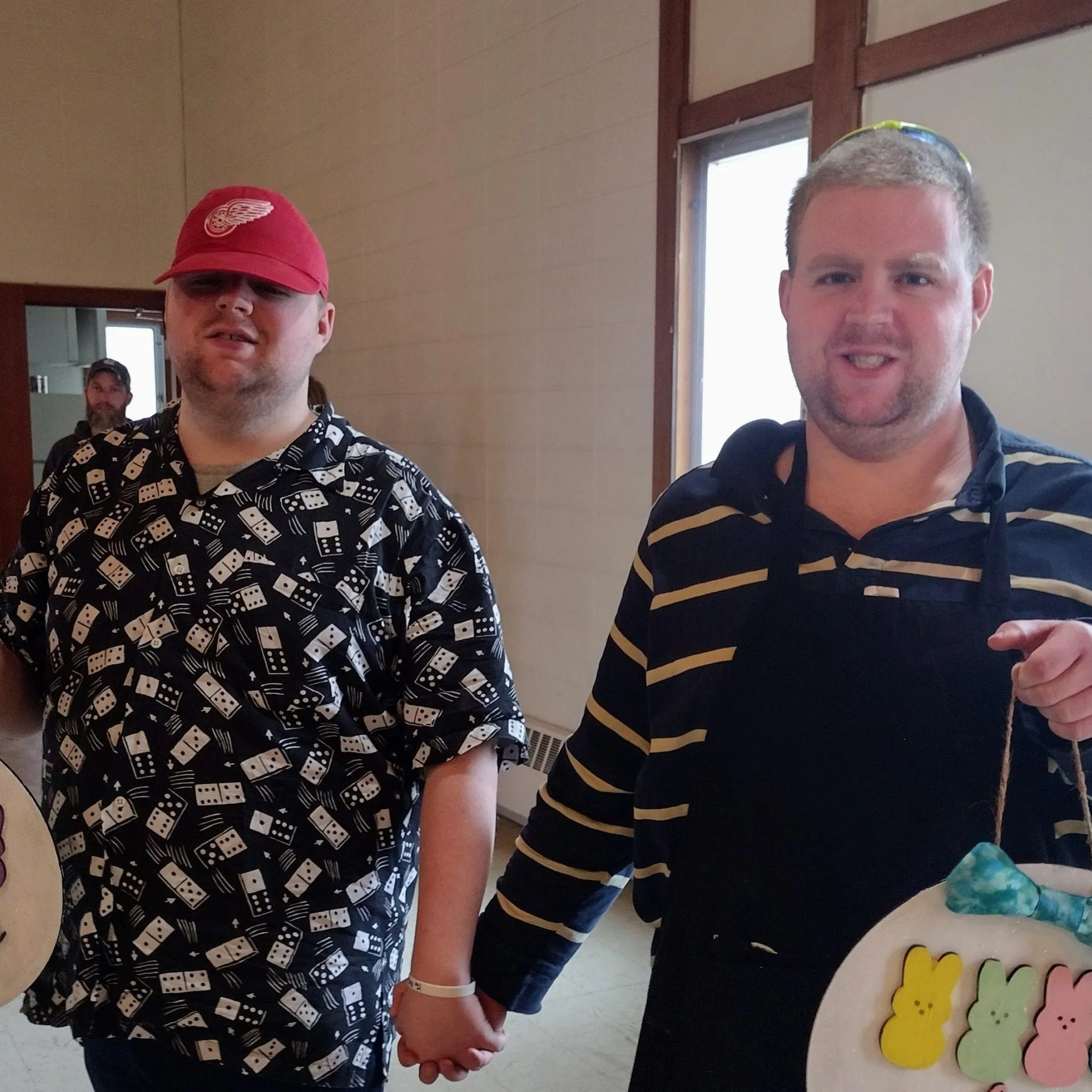 Two young men smiling and holding handmade craft signs they painted at an Xceptional Heroes activity.
